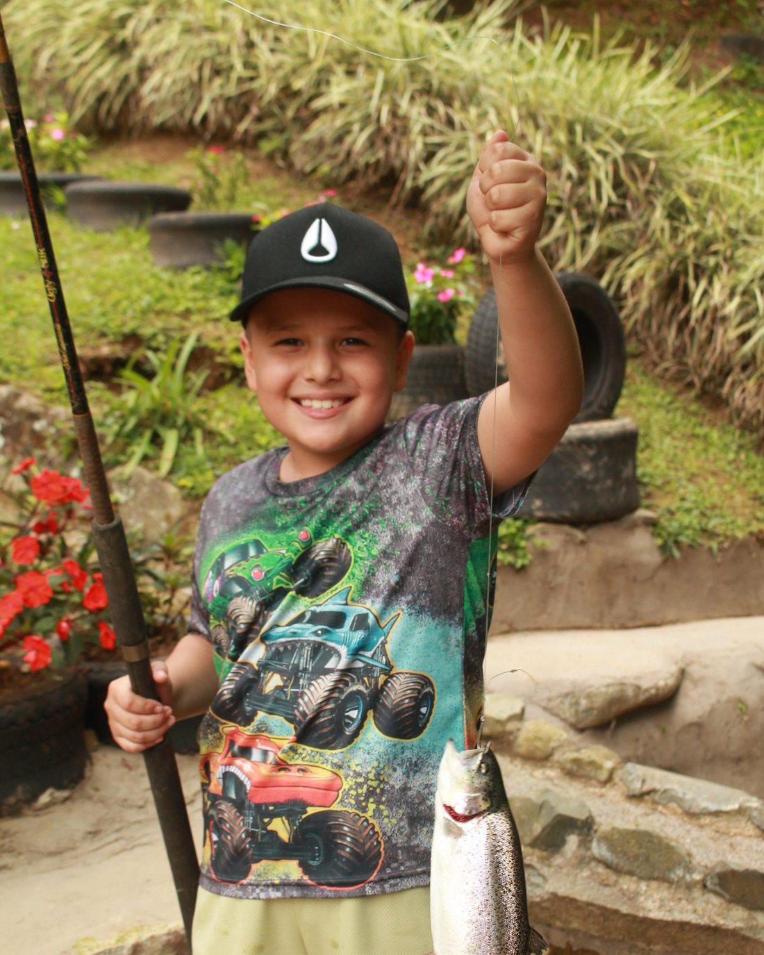 Niño sonriendo con la caña y la trucha recién pescada